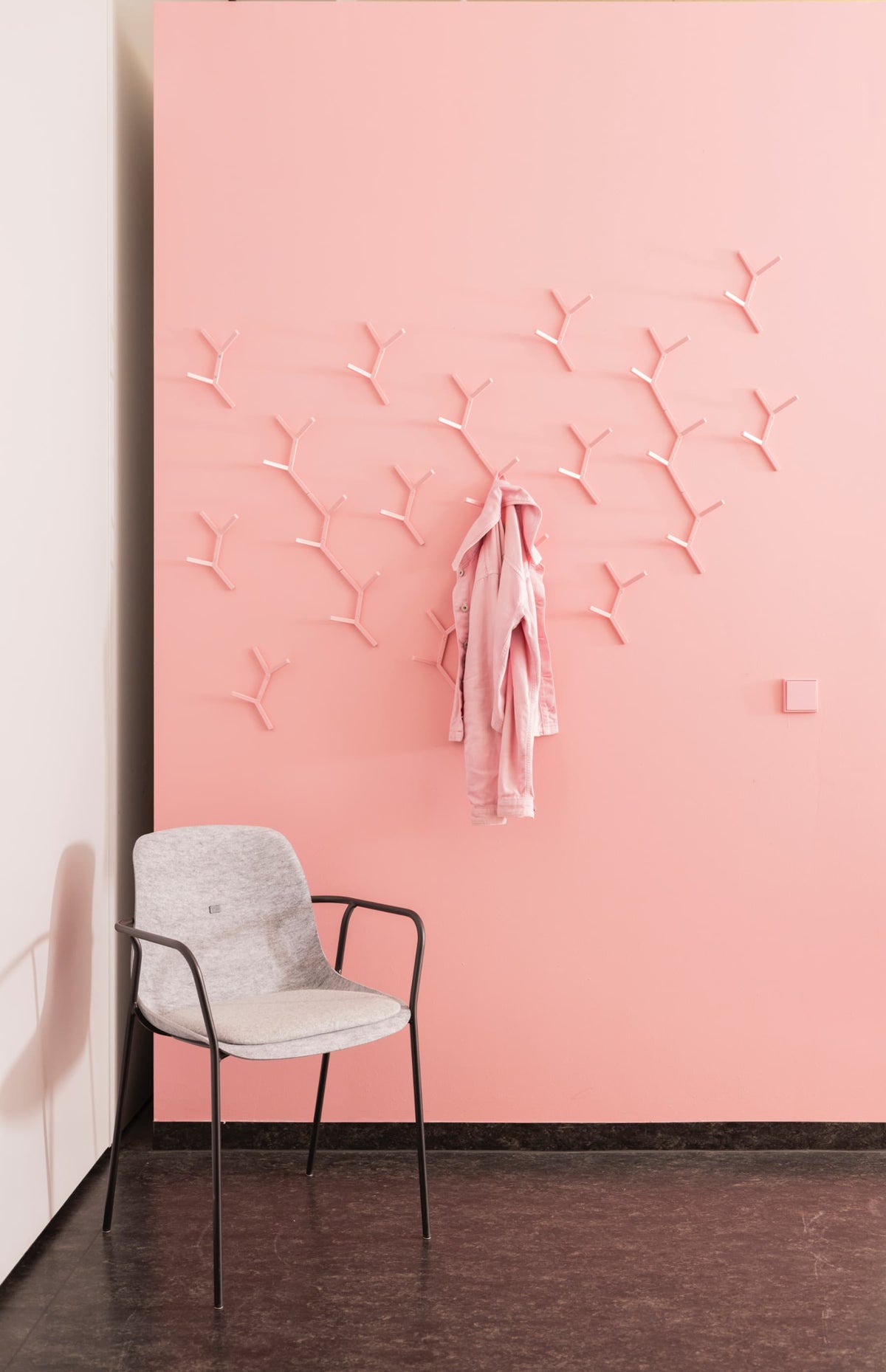 Rosa Design-Wandhaken als grafische Garderobenlösung an einer rosafarbenen Wand.