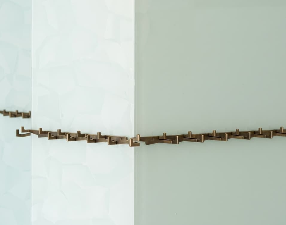 Bronzierte Wandgarderobe mit Mäander-Muster als Endlos-System montiert.