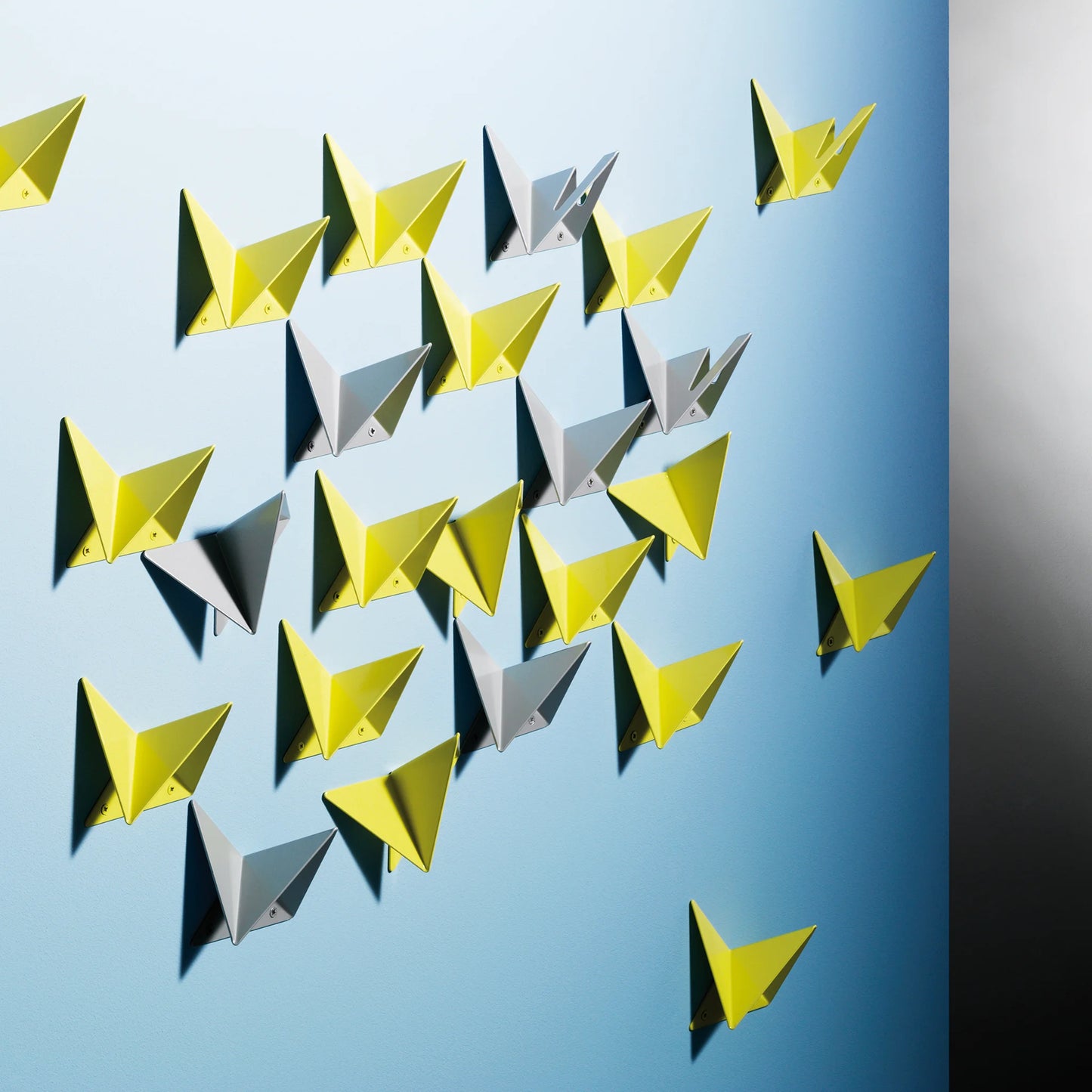Kombination verschiedener farbiger FLOCK Garderobenhaken an einer Wand montiert – zeigt das Zusammenspiel der geometrischen Faltungen.