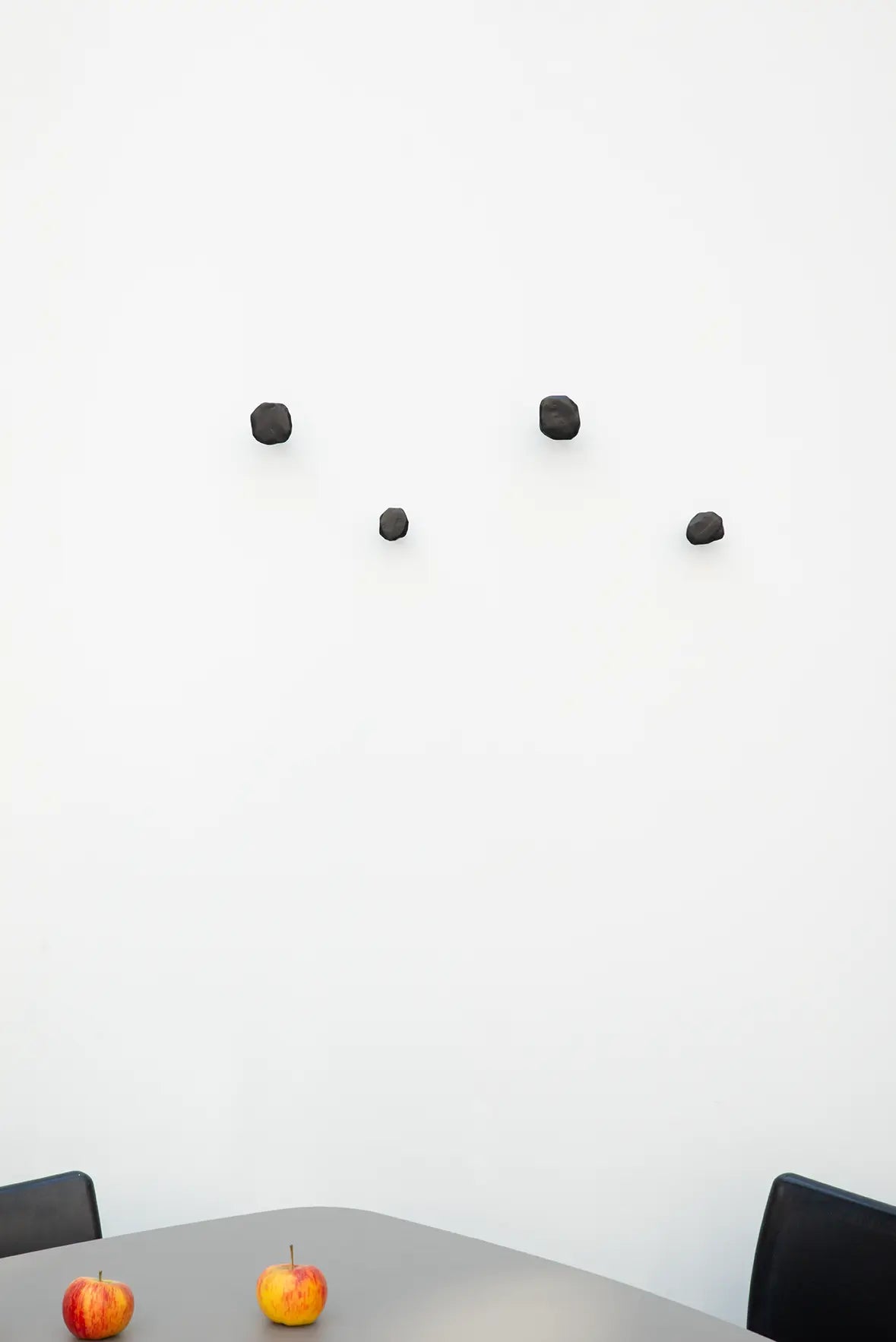 Vier schwarze Schmiedenagel-Stifthaken als minimalistische Garderobenhaken an einer weißen Wand montiert.